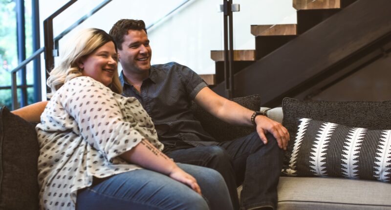 man and woman sitting on sofa smiling