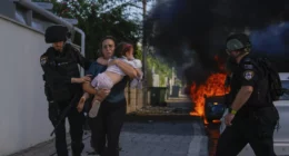 Sat, Oct. 7: Police officers evacuate a woman and a child from a site hit by a rocket fired from the Gaza Strip, in Ashkelon, southern Israel. Tsafrir Abayov/AP