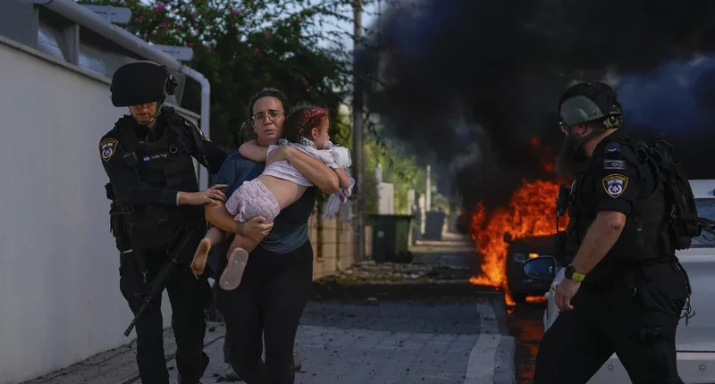 Sat, Oct. 7: Police officers evacuate a woman and a child from a site hit by a rocket fired from the Gaza Strip, in Ashkelon, southern Israel. Tsafrir Abayov/AP