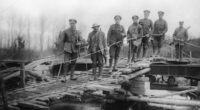 a group of men standing on top of a wooden bridge