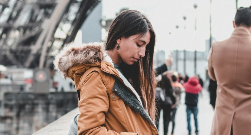 woman leaning against wall near Eiffel Tower