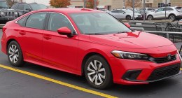 Honda Civic rojo de cuatro puertas, visto de frente y de lado, estacionado en un parqueadero
