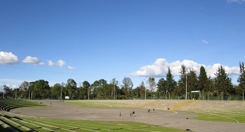 Escenario al aire libre del Parque Simón Bolívar de Bogotá, con gradas verdes y árboles al fondo