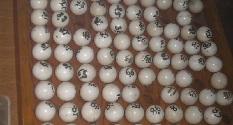 Bolas blancas numeradas de un juego de bolita, en una bandeja de madera