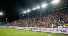 Estadio con público en la final de la Copa Libertadores Femenina 2021 en Montevideo, con la publicidad del torneo junto a la cancha