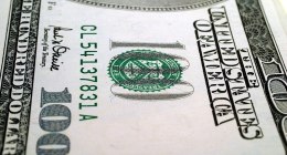 Primer plano de un billete estadounidense de 100 dólares, con el número de serie y el sello verde del Tesoro