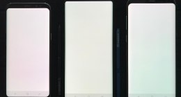 Tres teléfonos inteligentes con la pantalla encendida y en blanco, sobre fondo negro