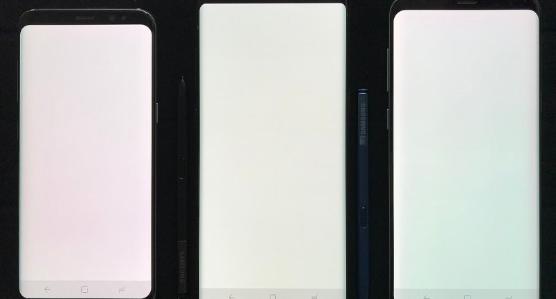Tres teléfonos inteligentes con la pantalla encendida y en blanco, sobre fondo negro