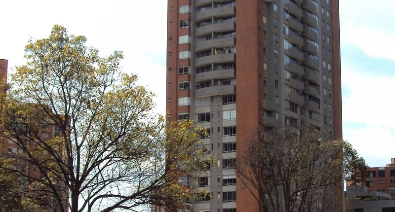 Torre residencial de ladrillo con balcones, en una avenida de Bogotá