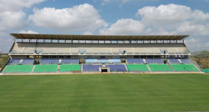 Tribuna del Estadio Jaraguay de Montería, con graderías azules y verdes vacías y la cancha de césped