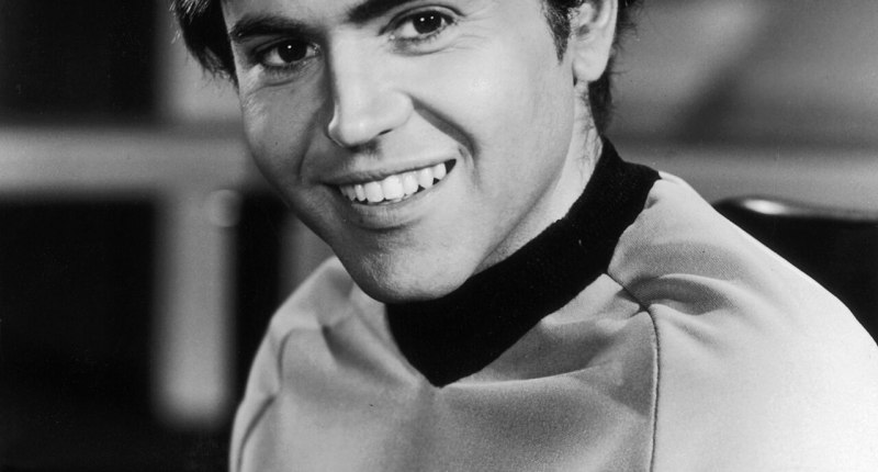 Walter Koenig sonriendo en blanco y negro, con el uniforme de la Flota Estelar de Star Trek