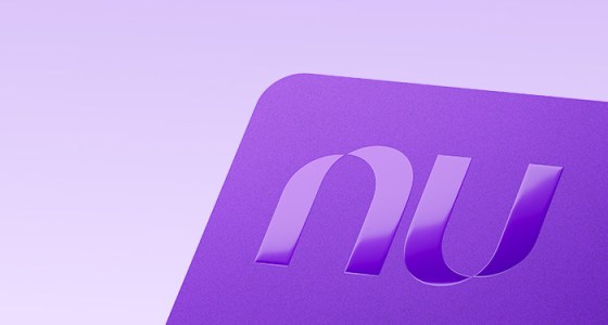 Tarjeta de crédito morada de Nu con el logo en relieve, sobre fondo lila