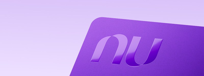 Tarjeta de crédito morada de Nu con el logo en relieve, sobre fondo lila