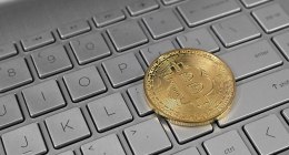 Moneda dorada de bitcoin sobre el teclado de un computador portátil