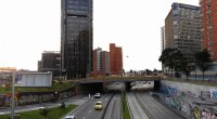 Avenida Calle 26 de Bogotá con poco tráfico, vista desde un puente peatonal, con edificios de oficinas y grafitis en los muros
