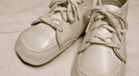 Un par de zapatos blancos de bebé de cuero con cordones, sobre una tela clara, en sepia