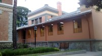 Edificio de un hospital con fachada color terracota y ventanas de madera, sin personas