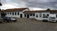 Fachada de un hospital público de Villa de Leyva, Boyacá, con dos ambulancias y otros vehículos estacionados en una plaza empedrada