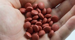 Tabletas rojas de un medicamento genérico sobre la palma de una mano