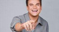 Silvestre Dangond, cantante, sonriente y señalando a cámara, sobre fondo gris