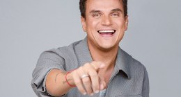 Silvestre Dangond, cantante, sonriente y señalando a cámara, sobre fondo gris