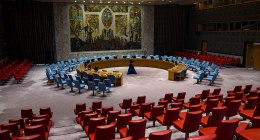 Sala del Consejo de Seguridad de la ONU en Nueva York, vacía, con las sillas rojas y azules y un mural al fondo