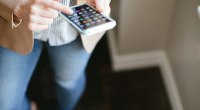 Mujer con un celular en la mano, con la pantalla llena de aplicaciones