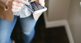 Mujer con un celular en la mano, con la pantalla llena de aplicaciones