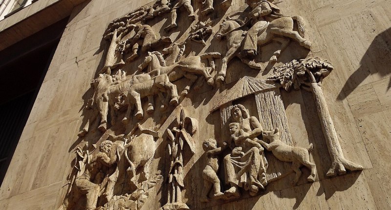 Altorrelieve de piedra en la fachada de un edificio de Bogotá, con figuras de campesinos, animales y una casa