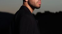 Anyma, productor y DJ, de perfil con camisa negra, con el cielo del atardecer de fondo