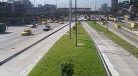 Avenida de Bogotá con varios taxis amarillos, buses y carros en circulación, y un separador con pasto y árboles