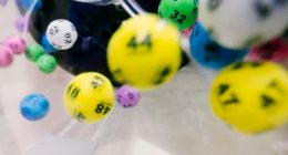 Bolas de lotería numeradas de colores girando dentro de una máquina transparente