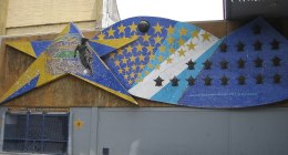 Mural de mosaico azul y amarillo con estrellas y un futbolista, junto a La Bombonera en Buenos Aires