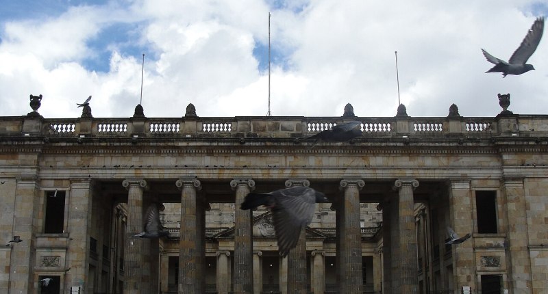 Fachada de columnas del Capitolio Nacional en Bogotá, con palomas en el cielo