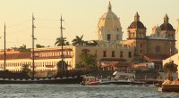 Bahía de Cartagena al atardecer, con la cúpula de una iglesia y un velero