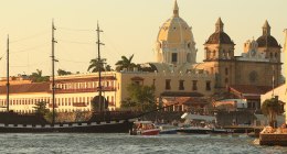 Bahía de Cartagena al atardecer, con la cúpula de una iglesia y un velero