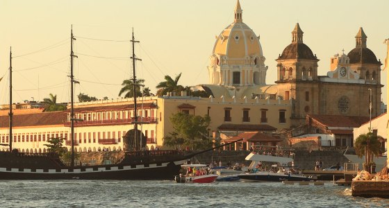 Bahía de Cartagena al atardecer, con la cúpula de una iglesia y un velero