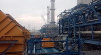 Central térmica de gas con chimeneas y estructuras de acero azul, con humo saliendo de una de ellas