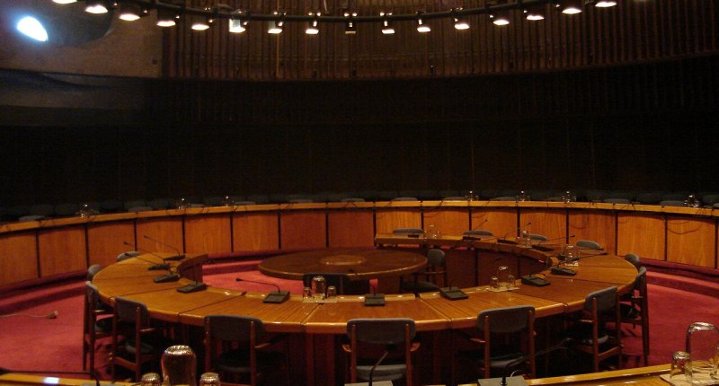 Sala de reuniones vacía con mesa circular de madera y micrófonos, en la sede de la CEPAL en Santiago