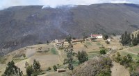 Humo de un incendio forestal sobre una montaña quemada, con un pueblo con iglesia blanca en la ladera (Chíquiza, Boyacá)