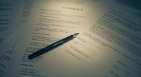 Contrato con una pluma estilográfica sobre el documento, con espacios para la firma