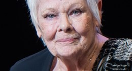 Retrato de la actriz Judi Dench, con cabello corto y blanco y blusa negra, sobre fondo oscuro