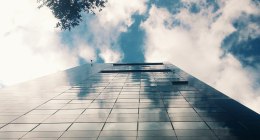 Torre de vidrio de la Bolsa de Valores de Colombia, vista desde abajo, con nubes reflejadas