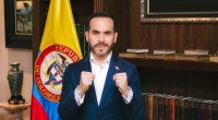 Abelardo de la Espriella frente a una bandera de Colombia y una biblioteca, con los puños cerrados