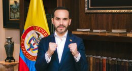 Abelardo de la Espriella frente a una bandera de Colombia y una biblioteca, con los puños cerrados