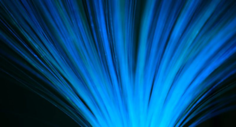 Cables de fibra óptica azules que se abren en abanico sobre fondo oscuro