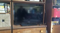 Televisor de pantalla plana negro sobre un mueble de madera, en una sala