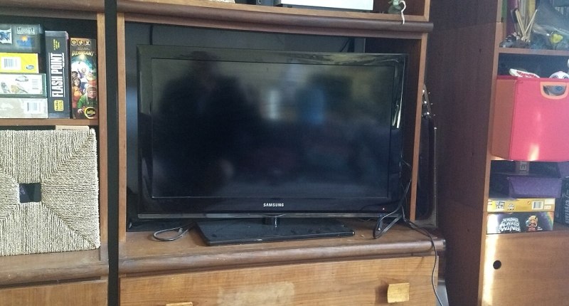 Televisor de pantalla plana negro sobre un mueble de madera, en una sala