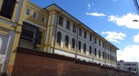 Fachada amarilla y blanca del Hospital de San José en Bogotá, con muro de ladrillo sobre la calle