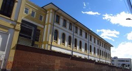 Fachada amarilla y blanca del Hospital de San José en Bogotá, con muro de ladrillo sobre la calle